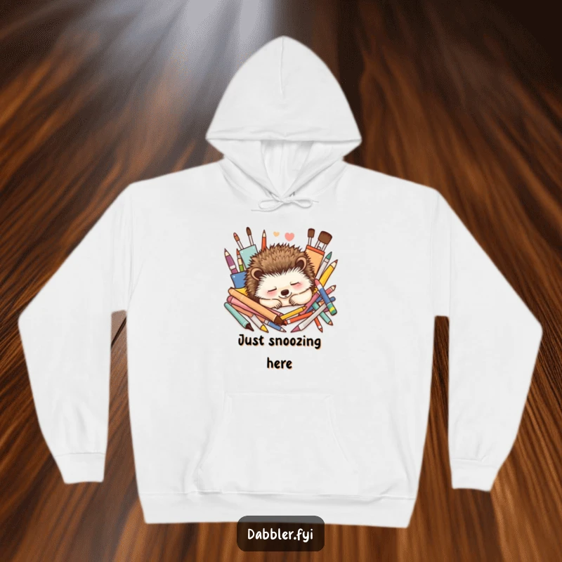 Funny Hoodie: A contented hedgehog naps peacefully amidst a delightful array of colorful art supplies, radiating calm.