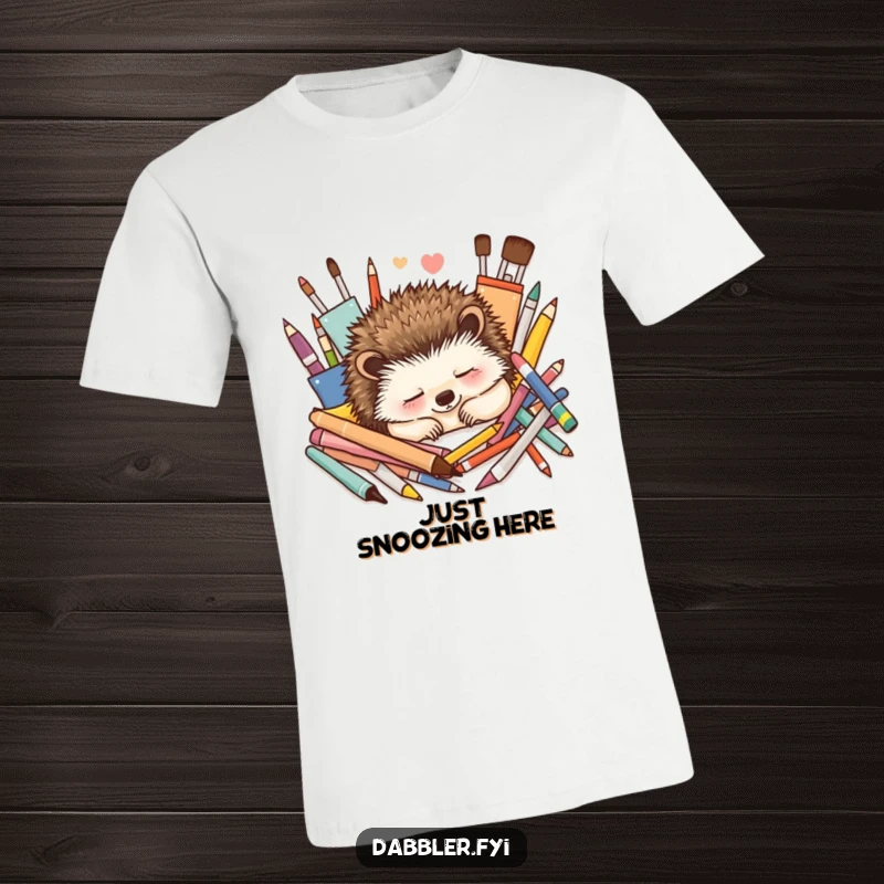 Funny T-Shirt: A contented hedgehog peacefully naps among colorful art supplies, exuding blissful relaxation and artistic vibes.
